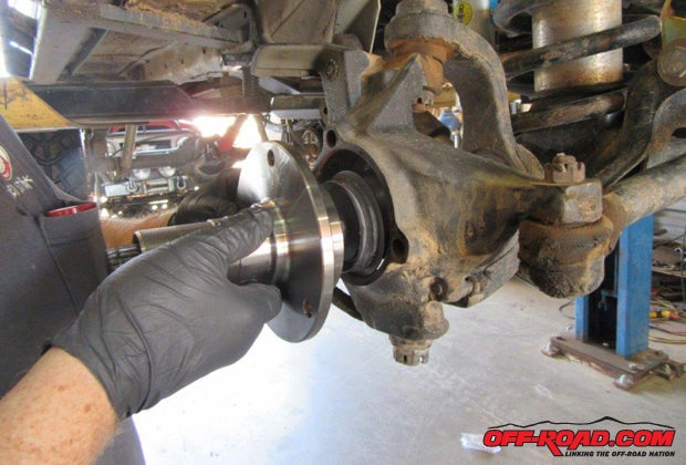 Install the plastic fiber washer on the inward side of the spindle, slide the spindle over the axle shaft, and bolt the spindle onto the differential housing using the original bolts. Use Loctite on the bolts and torque them to 75 lb.-ft.