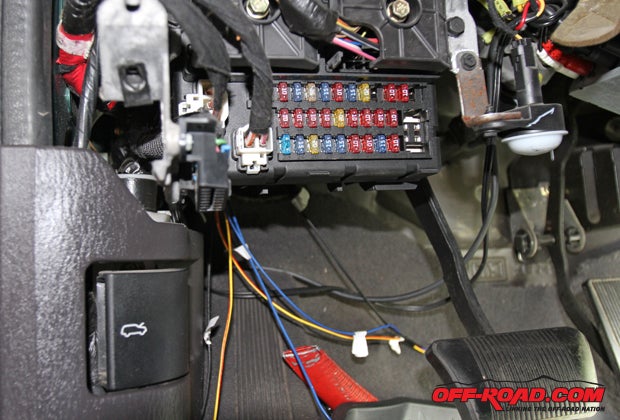 With the wires for each locker connected and safely routed underneath the vehicle, the wiring was run through the fire wall access on the drivers side just behind the fuse box  those are the yellow and blue wires hanging down.